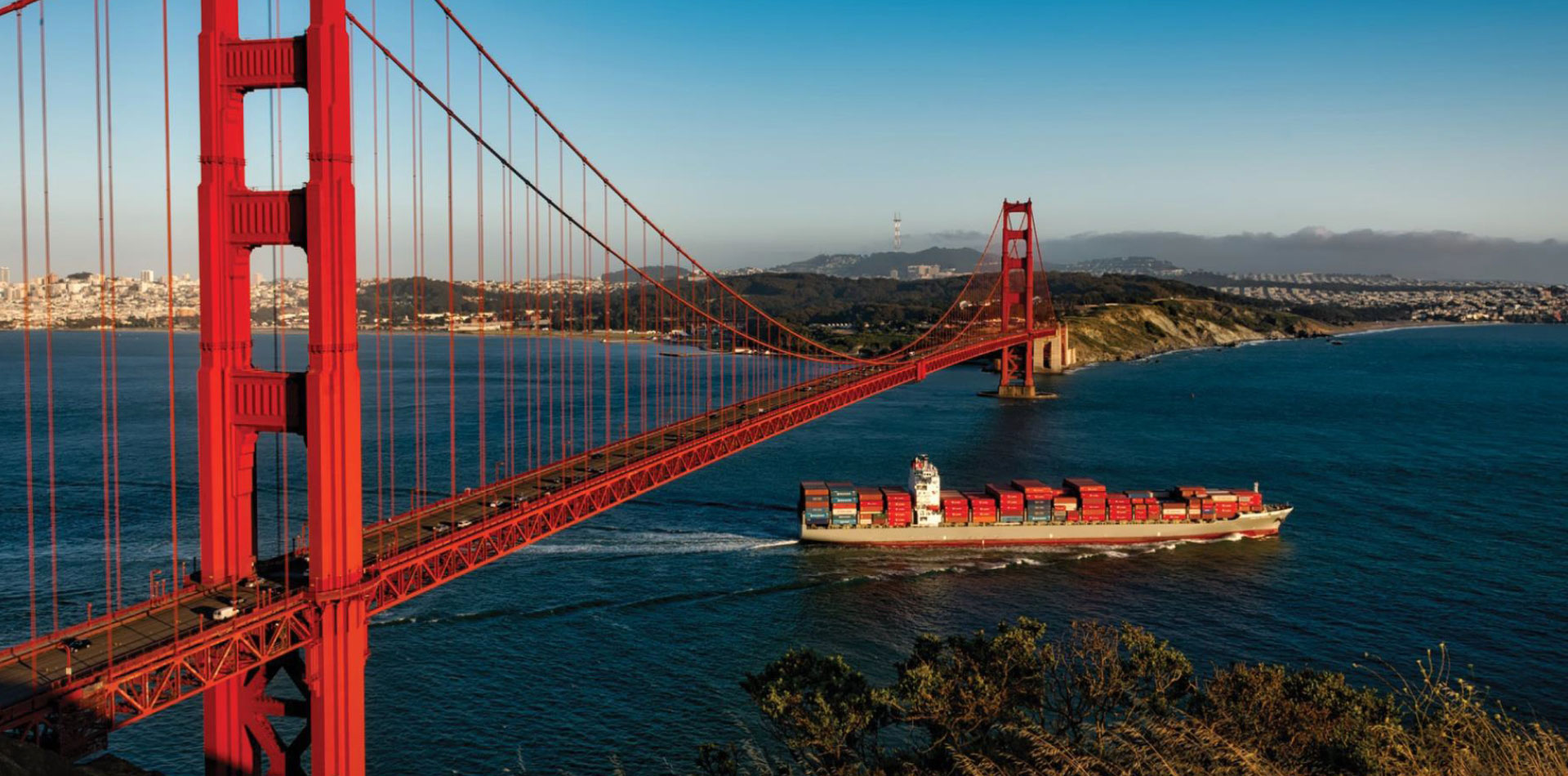 A seaspan ship passing under the Golden Gate Bridge